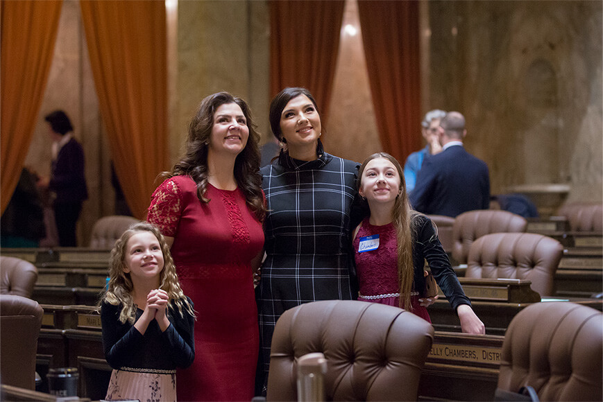 Kelly Chambers smiling and posing with three young women at a county meeting