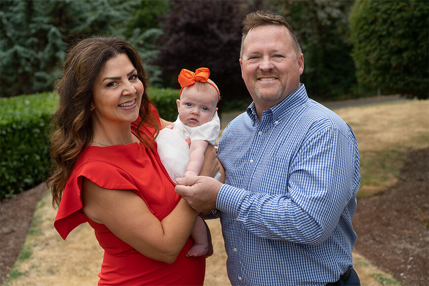 Kelly Chambers and her husband holding their infant granddaughter