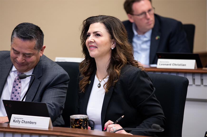 Kelly Chambers sitting behind a desk at a county meeting